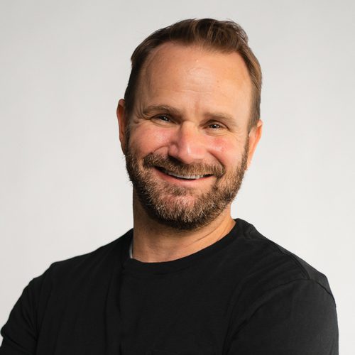 Smiling man with a beard in a black shirt, representing innovation and leadership in medical device development at C3 Medical.